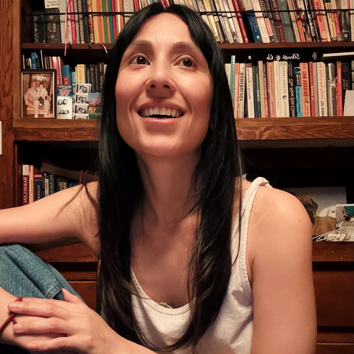 Sara(h), creator of The Number Witch, smiling in front of a wall of books